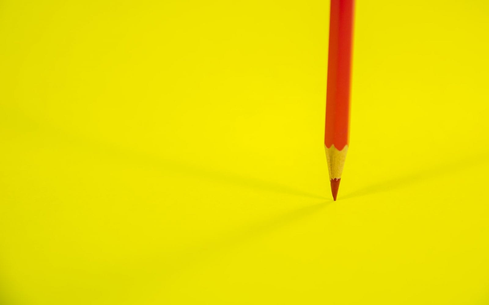 red pencil on yellow surface
