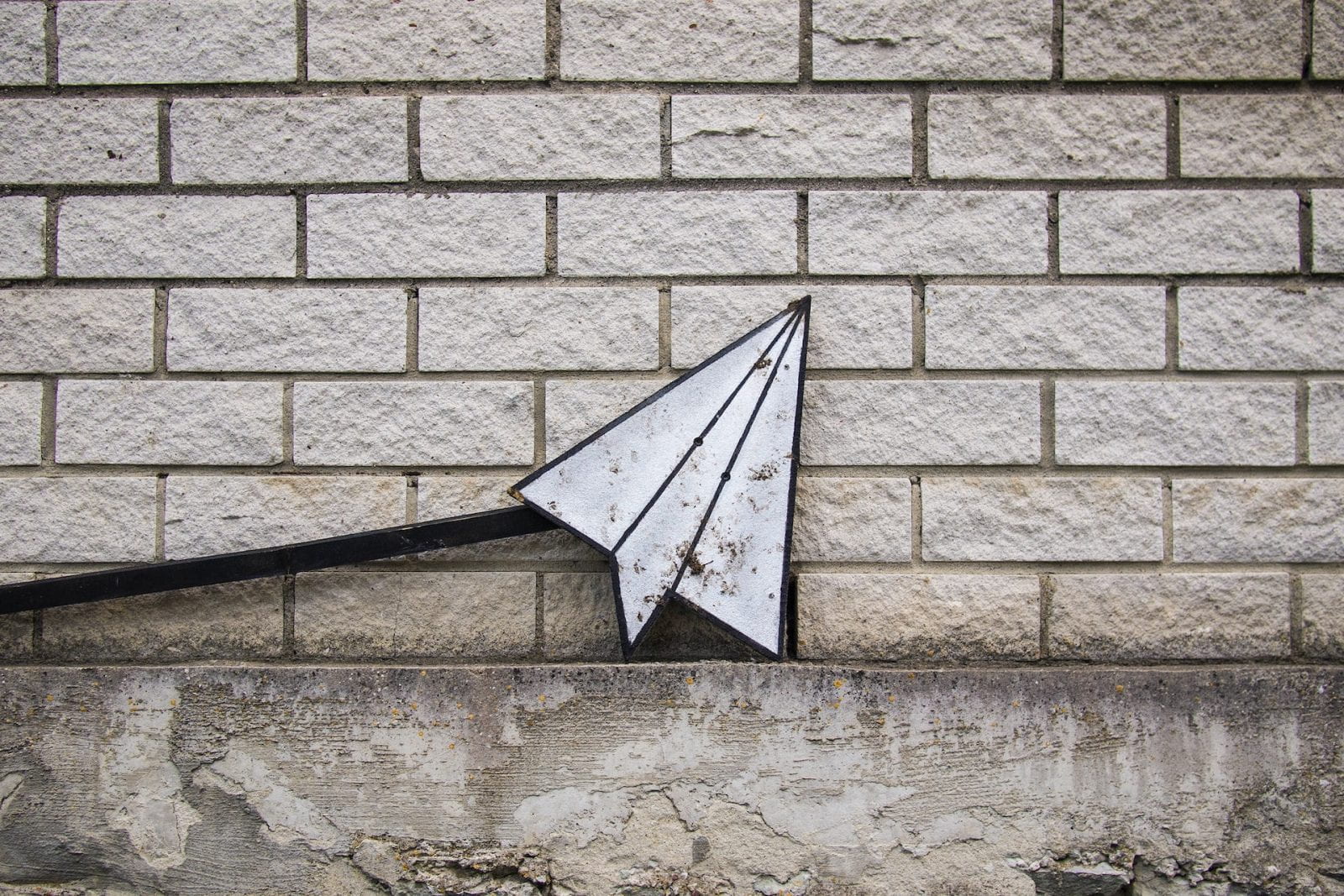 Image of a brick wall with a folded up paper airplane