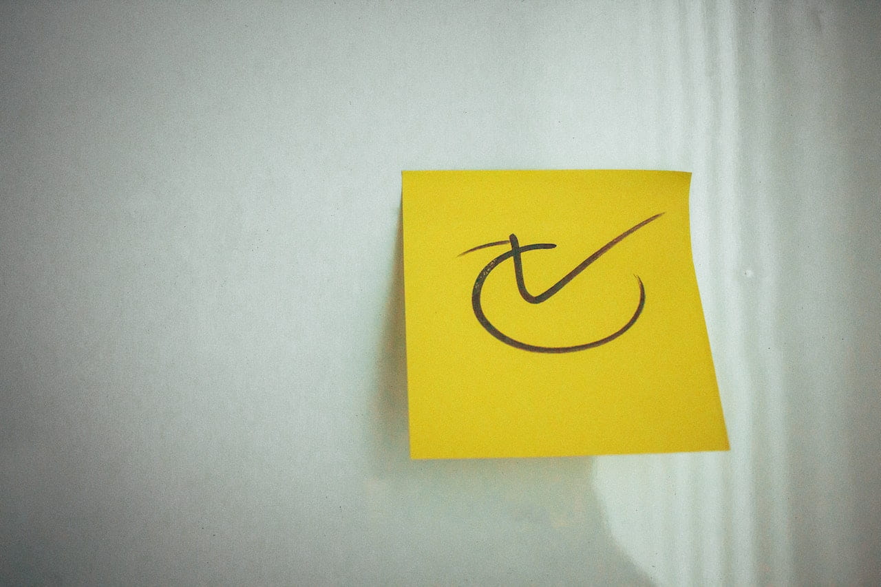 Black checkmark on a yellow post-it note